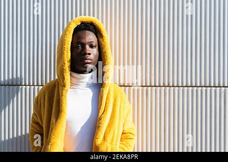 Young man in yellow jacket against white wall Stock Photo