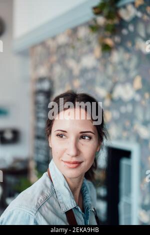 Thoughtful female owner looking away in coffee shop Stock Photo