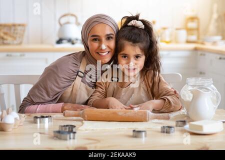Portrait Of Happy Muslim Family Mom And Little Daughter Baking In Kitchen Stock Photo