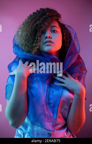 Fashionable woman with scarf around hair against purple background Stock Photo