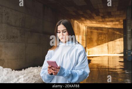 Woman using mobile phone while standing against tunnel Stock Photo