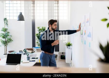 Young businessman analyzing strategies while standing against wall in office Stock Photo