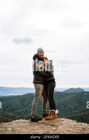 Happy couple hugging each other at viewpoint against sky Stock Photo
