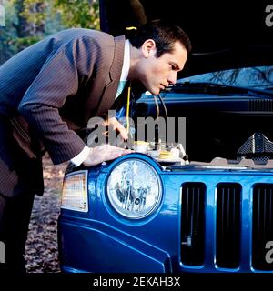 Businessman looking under hood of a car Stock Photo