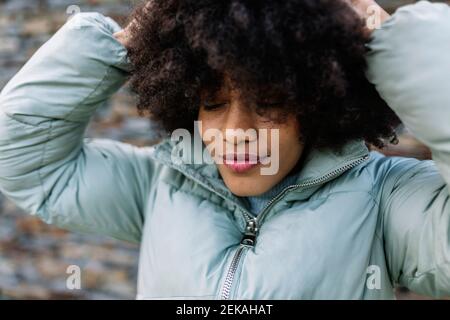 Afro woman with hand in hair and eyes closed outdoors Stock Photo
