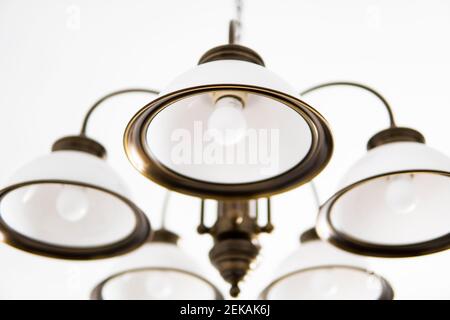 Bronze chandelier with five white glass lamp shades on a ceiling in a bedroom. Interior design. Stock Photo