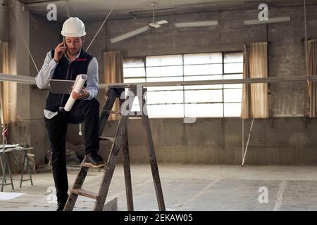 Male architect discussing over mobile phone while using digital tablet in building Stock Photo