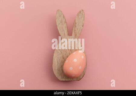 Minimal easter holiday background. Wooden easter bunny and egg on pink Stock Photo