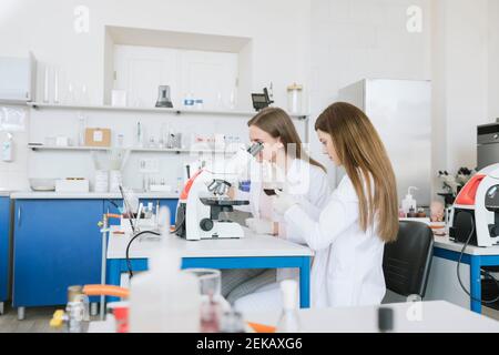 Scientists in white coats doing experiment in lab Stock Photo