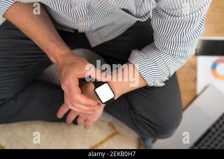 Businessman using smart watch while sitting at home Stock Photo