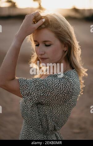 Thoughtful female standing at beach during sunset Stock Photo