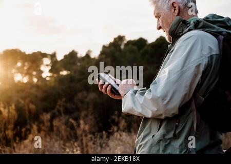 Senior man using smart phone during sunset Stock Photo