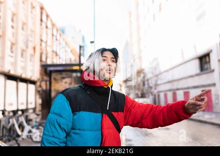 Male hipster hailing ride on street in city Stock Photo