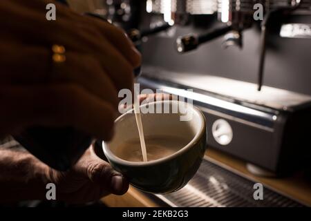 Barista pouring milk while making coffee at cafe Stock Photo