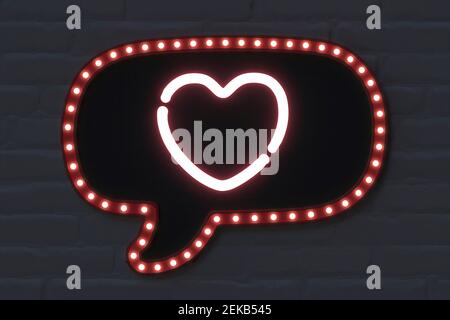 Illuminated speech bubble with heart shape on black brick wall Stock Photo