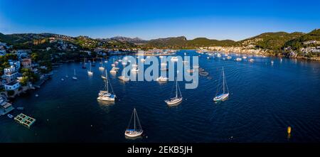 Spain, Mallorca, Andratx, Helicopter view of boats sailing near shore of coastal town at summer dusk Stock Photo