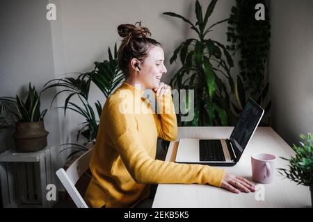 Smiling woman talking with friends over digital tablet on video conference while sitting at home Stock Photo