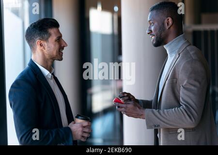 Smiling businessmen having discussion while standing in office Stock Photo