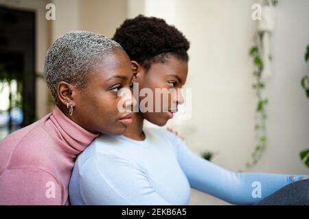 Thoughtful female friends looking away at home Stock Photo