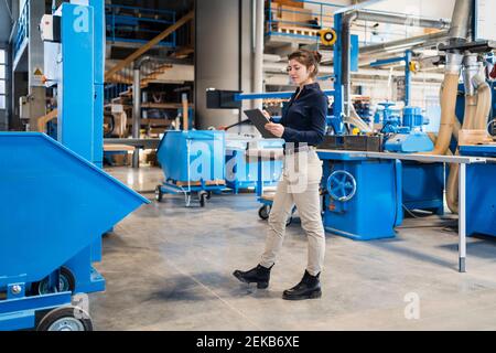 Businesswoman using digital tablet while walking at industry Stock Photo