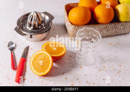 Empty drinking glass with orange and stainless steel steel juicer kept on modern marble Stock Photo