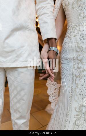 Bride and groom in wedding dress holding hands while standing at banquet Stock Photo