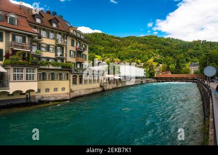 Wooden bridge over river by old buildings in Thun, Switzerland Stock Photo