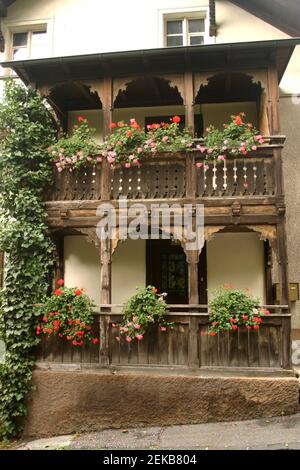 Facade of a house in Liechtenstein, with beautifully carved wooden balcony and decorative flowers Stock Photo
