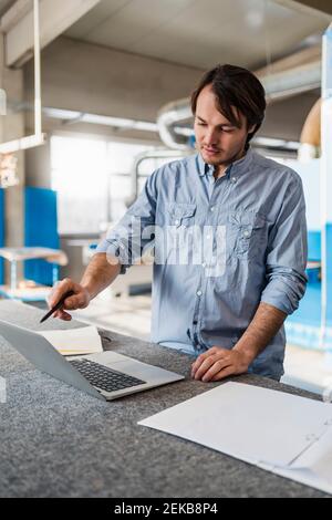 Young businessman using laptop while working at industry Stock Photo