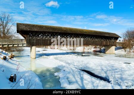 The all wood lattice covered pedestrian & cyclist covered bridge over the Eramosa River in winter built in 1992. Guelph Ontario Canada Stock Photo