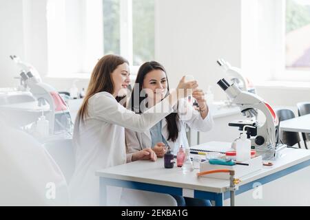 Young female researchers in white coats analyzing laboratory sample in lab Stock Photo
