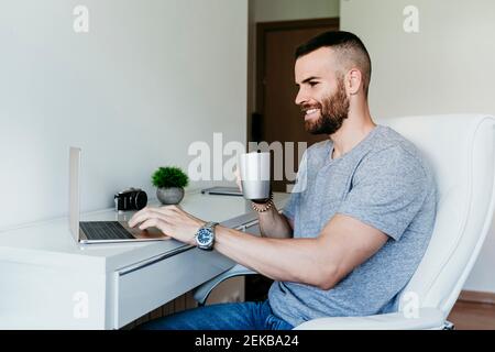 Smiling man working on laptop at home Stock Photo
