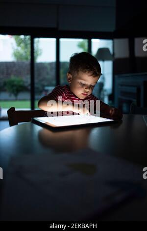 Boy using digital tablet while sitting at table in home Stock Photo