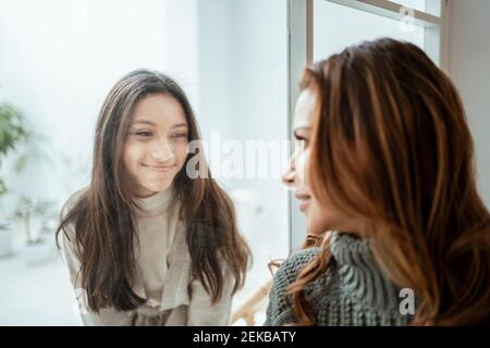 Smiling girl looking at mother through window at home Stock Photo