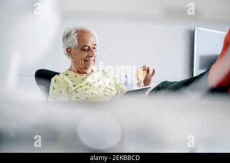 Smiling businessman using digital tablet while sitting at office Stock Photo