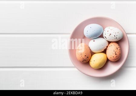 Chocolate easter eggs. Sweet candy eggs on pink plate on white table. Top view. Stock Photo