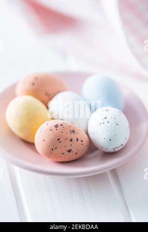 Chocolate easter eggs. Sweet candy eggs on pink plate on white table. Stock Photo