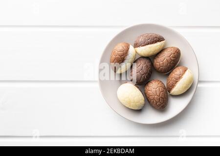 Chocolate easter eggs. Sweet candy eggs on white table. Top view. Stock Photo