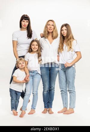 Confident mothers and daughters standing against white background in studio Stock Photo