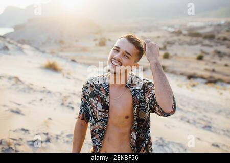 Happy handsome man wearing unbuttoned shirt in desert at at Almeria, Tabernas, Spain Stock Photo