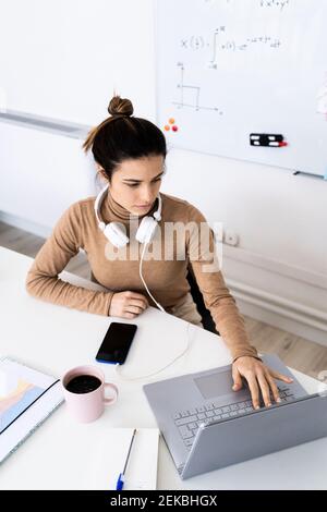 Female student with headphones using laptop while studying at home Stock Photo