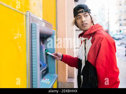 Asian man withdrawing money from ATM machine Stock Photo