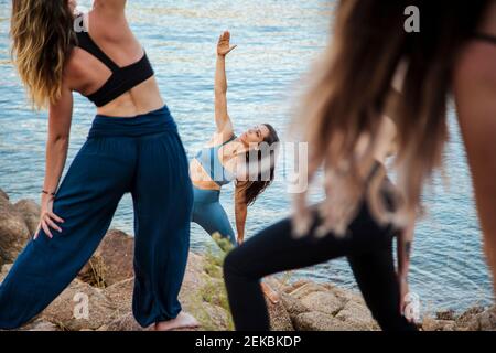 Young female yoga instructor teaching stretching exercise to women Stock Photo