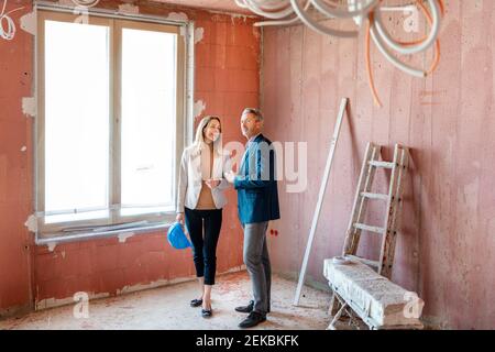 Male engineer and businesswoman working together while examining construction site Stock Photo