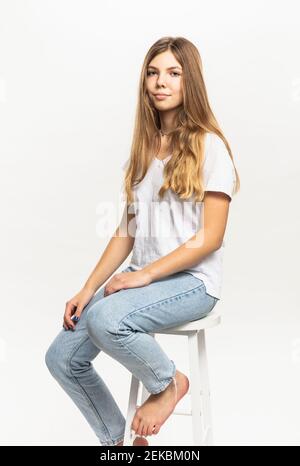 Pre-adolescent girl sitting on stool against white background in studio Stock Photo