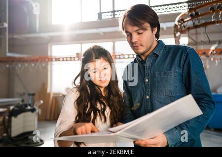 Smiling colleagues discussing document while standing at industry Stock Photo