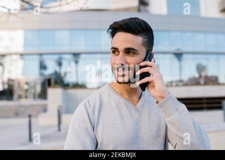 Handsome young man talking on smart phone while looking away Stock Photo