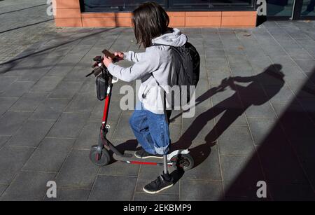 Young disabled man using smart phone while standing on electric push scooter during sunny day Stock Photo