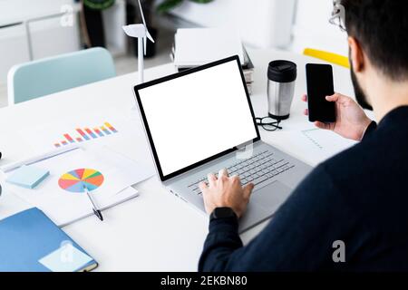 Young businessman using laptop and smart phone in creative office Stock Photo