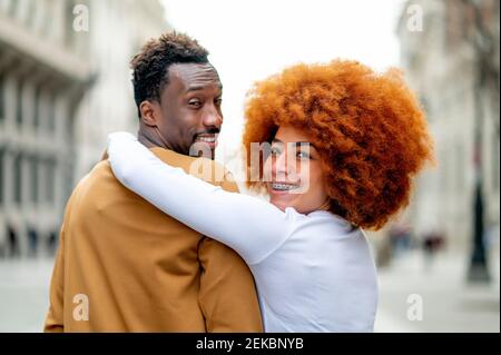 Smiling girlfriend with arm around on boyfriend standing outdoors Stock Photo